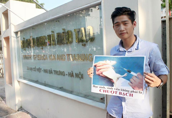 Nguyễn Thành Nhân cầm tấm biển: “Học sinh, sinh viên, không phải là chuột bạch” trước cổng Bộ Giáo dục và Đào tạo.[VOA]